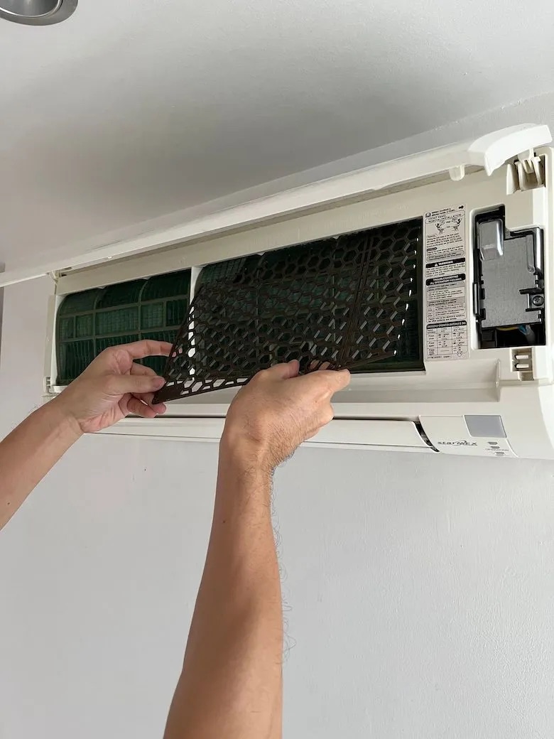Bizsu installer fitting a CONTINEWM net above the filter of a wall-mounted air conditioner